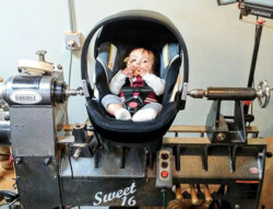 Baby in a baby carrier on a lathe By Doug Rowe